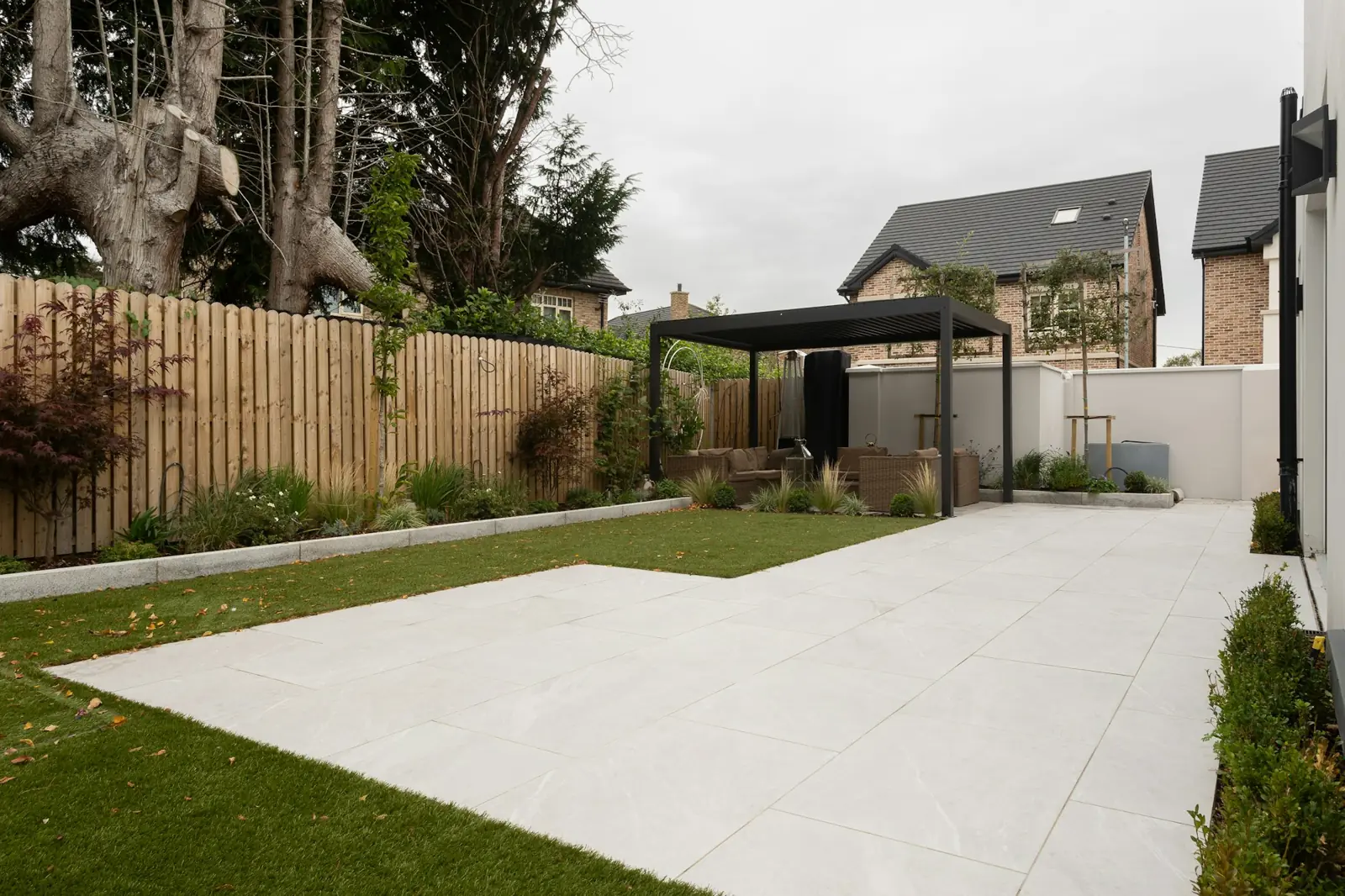 Wide porcelain patio and lawn bordered by new fencing